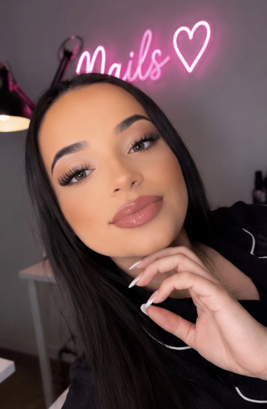 Omii in her nail lounge, under her neon Nails sign